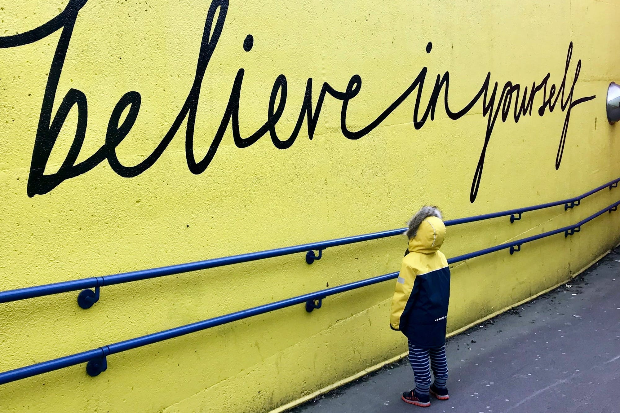 toddler looking at believe in yourself graffiti