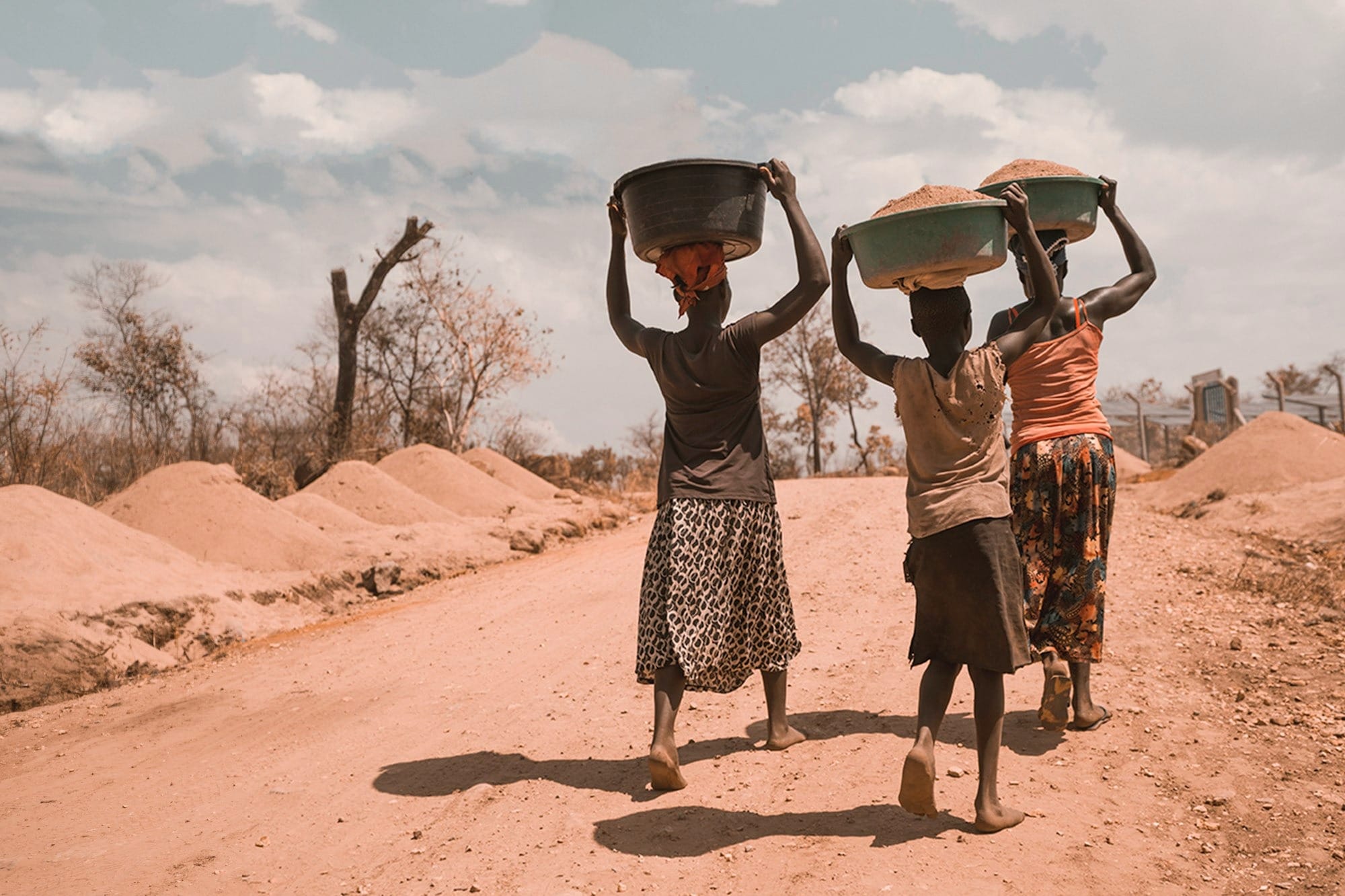 three women carrying basin while walking barefoot